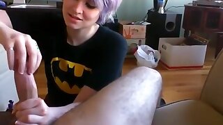 Batgirl Jerks Him Off And Swallows, This alternative batgirl looks sweet while kneeling in front of her guy and giving him an adorable handjob with both of her hands. She jerks him off for quite a while and swallows all of his cum when he climaxes.